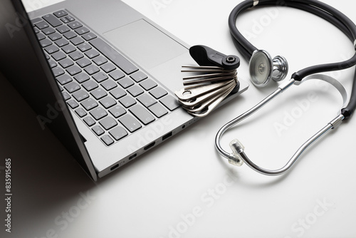 Tool and stethoscope on laptop, closeup. Concept of technical support
