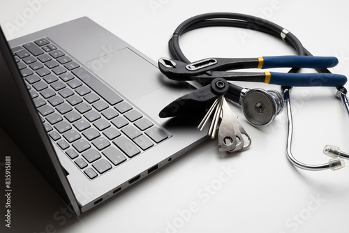 Spanner and stethoscope on laptop, closeup. Concept of technical support