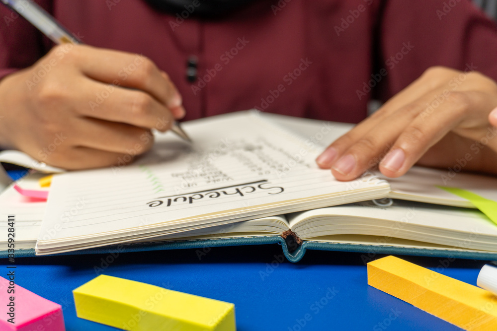 front view of person writing a daily activity schedule in a notebook on table front view of person writing a daily activity schedule in a notebook on table