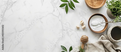 Top view of natural ingredients and kitchen items on marble countertop including honey, garlic, leaves, and wooden bowls for cooking or skincare.