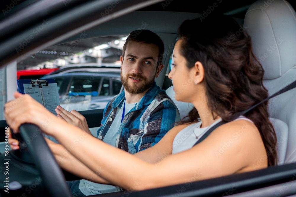 Young ladu studying in driving school while looking at male instructor during driving test. Test drive, transportation, safety, education concept