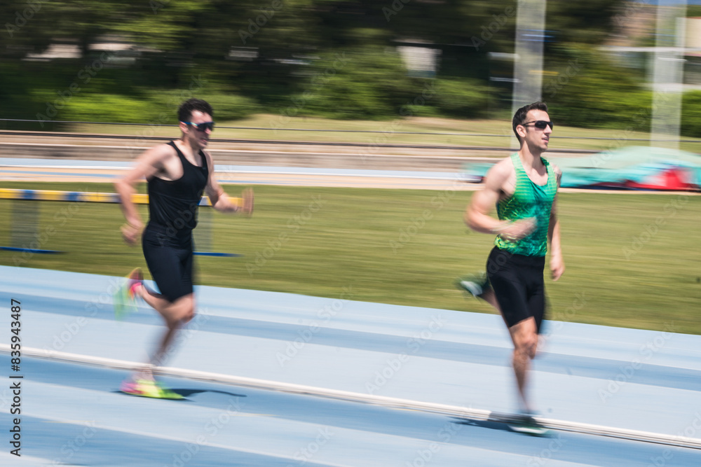 Two men are running on a track. They are on the finishing straight of a race