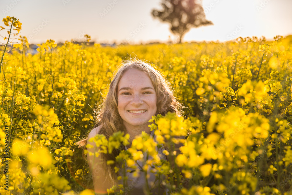 Teenage girl smiling among canola crop on farm Teenage girl smiling among canola crop on farm