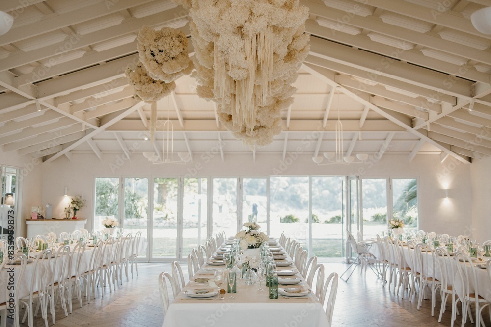 Table adorned with white chairs and flowers for an event Table adorned with white chairs and flowers for an event