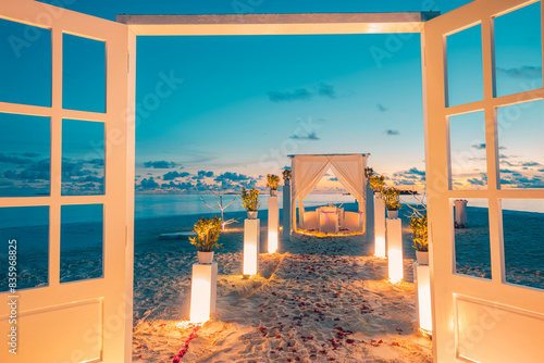 Beautiful decoration table setup for wedding ceremony on sunset beach. Romantic destination dining, couple anniversary romance celebration. Love arrangement togetherness dinner on island beach shore