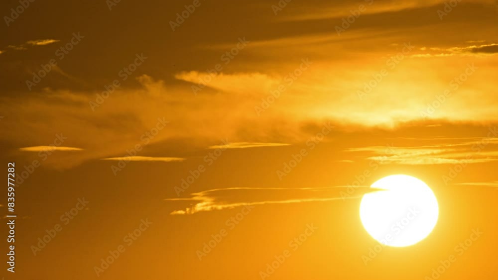 Timelapse shot of the bright orange sun sets behind the clouds Timelapse shot of the bright orange sun sets behind the clouds