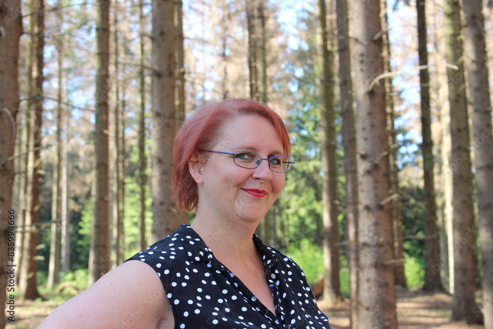 Portrait of a red-haired cheerful woman in the forest on a beautiful sunny summer day Portrait of a red-haired cheerful woman in the forest on a beautiful sunny summer day