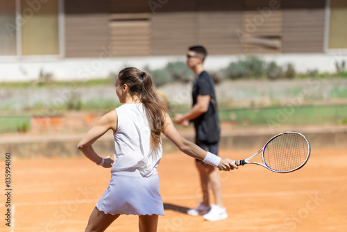 A woman is playing tennis with a man watching her © KONSTANTIN SHISHKIN