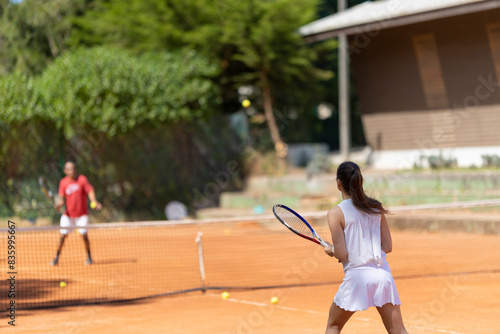 A woman is playing tennis with a man