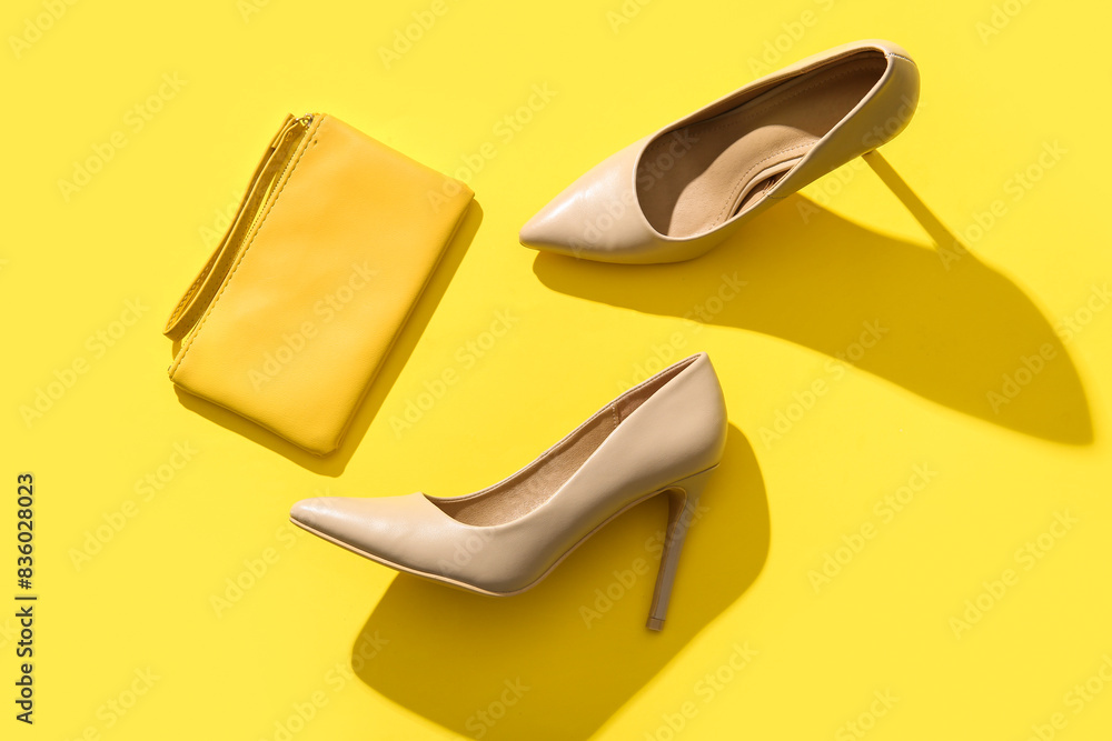 Pair of stylish high-heeled shoes and clutch on yellow background Pair of stylish high-heeled shoes and clutch on yellow background