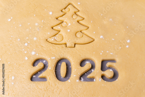 New year 2025. Cooking homemade cookies. Cutting out cookies in shape of the number 2024 and Christmas tree.