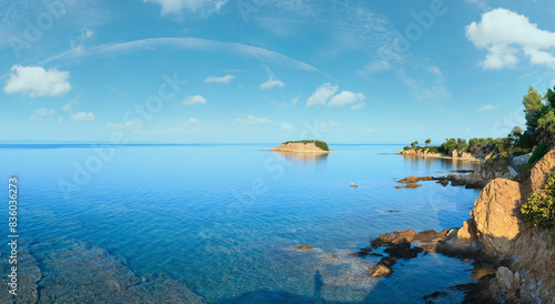 Morning Aegean Sea rocky coast view with shadow of photographer on clear water surface (Nikiti, Sithonia, Halkidiki, Greece). Two shots stitch panorama.