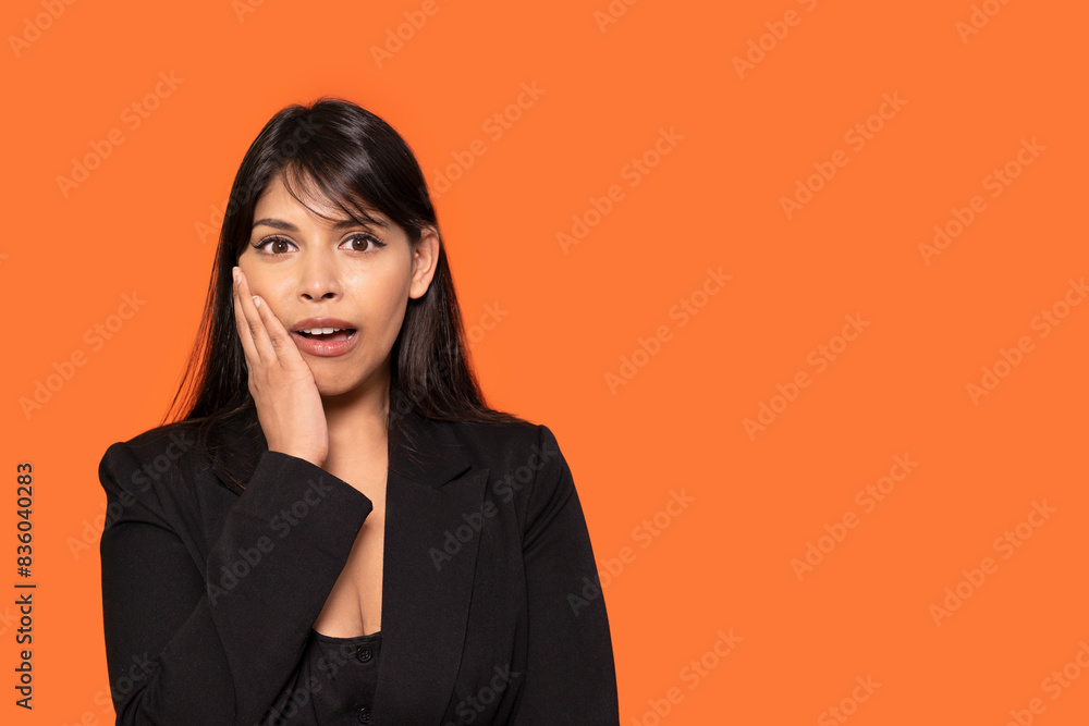 Woman with hand on cheek hearing unbelievable news on orange background Woman with hand on cheek hearing unbelievable news on orange background