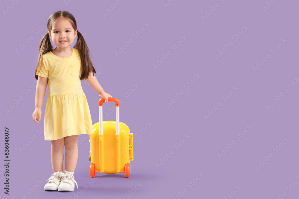 Cute little Asian happy girl with toy suitcase on purple background Cute little Asian happy girl with toy suitcase on purple background