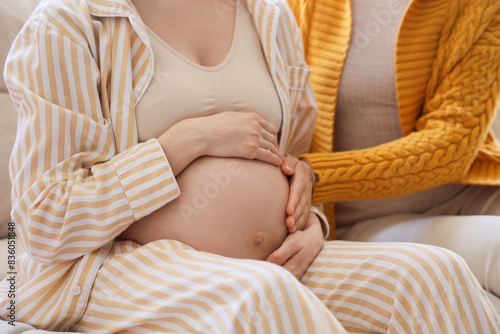 Young pregnant woman with doula sitting on sofa at home, closeup