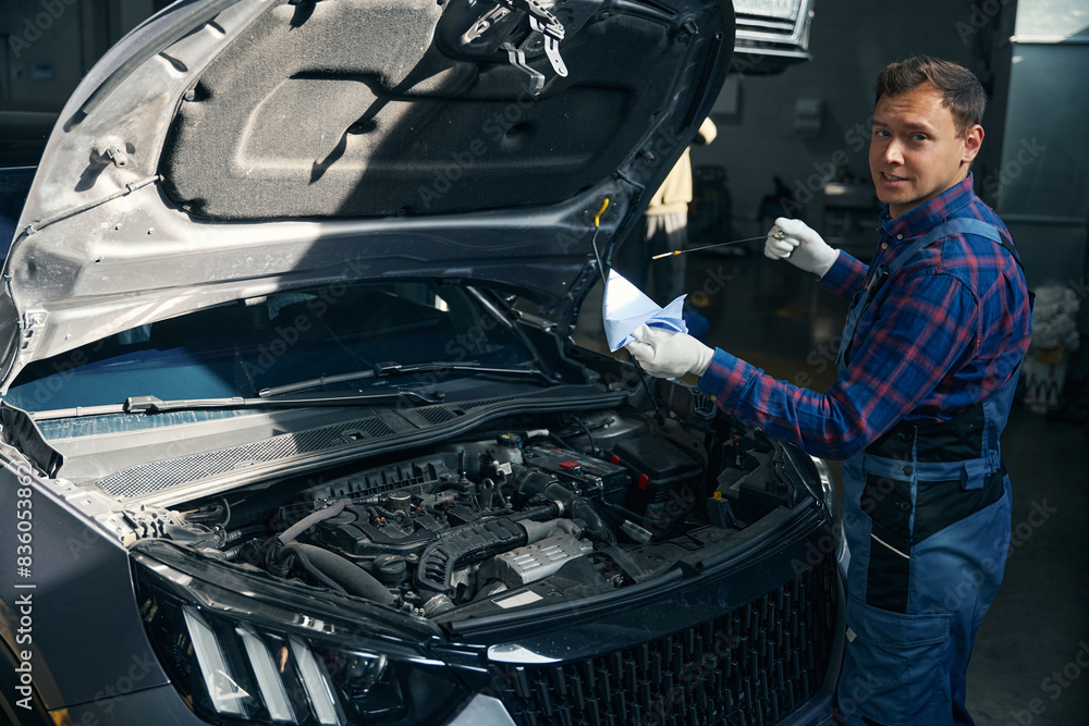 Fototapeta premium Man checking oil level in vehicle engine