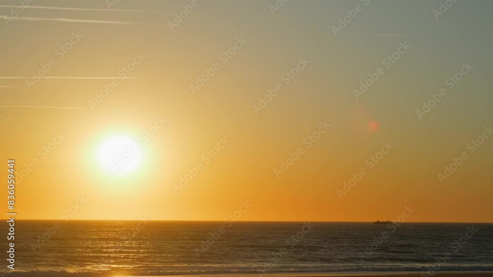Contemplation of the sea waves during sunset. Low angle view of Ocean shore with rolling waves with an orange sun on the horizon while sunset. Sandy beach with rolling waves during sunset in summer. Contemplation of the sea waves during sunset. Low angle view of Ocean shore with rolling waves with an orange sun on the horizon while sunset. Sandy beach with rolling waves during sunset in summer.