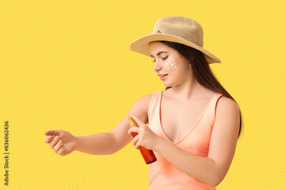 Young woman applying sunscreen on yellow background Young woman applying sunscreen on yellow background