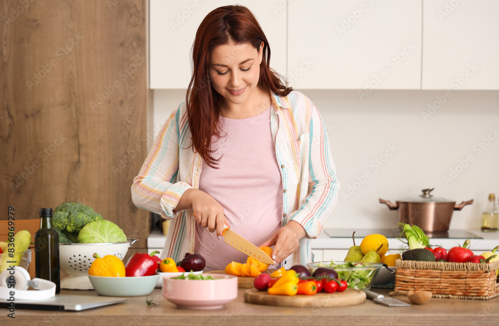 Young pregnant woman cutting fresh vegetables for salad in kitchen Young pregnant woman cutting fresh vegetables for salad in kitchen