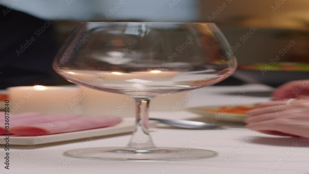 Vertical shot of hands of unrecognizable man adding red wine to glass of his wife during romantic dinner Vertical shot of hands of unrecognizable man adding red wine to glass of his wife during romantic dinner