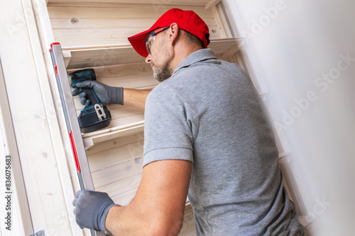 Obraz na plátne Man Installing Wooden Shelves With Power Drill