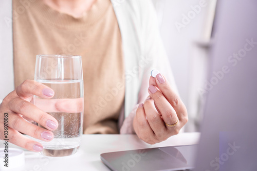 Photos closeup woman hand taking paracetamol medicine with a glass of water to relief h