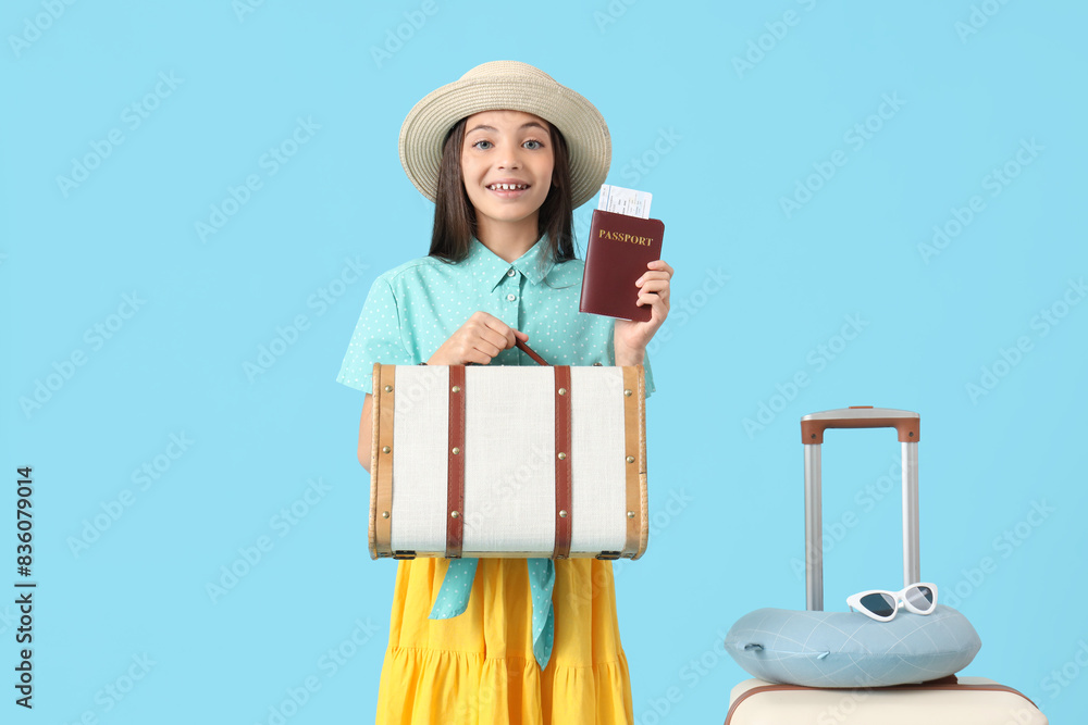 Cute little tourist with passport and bags on blue background