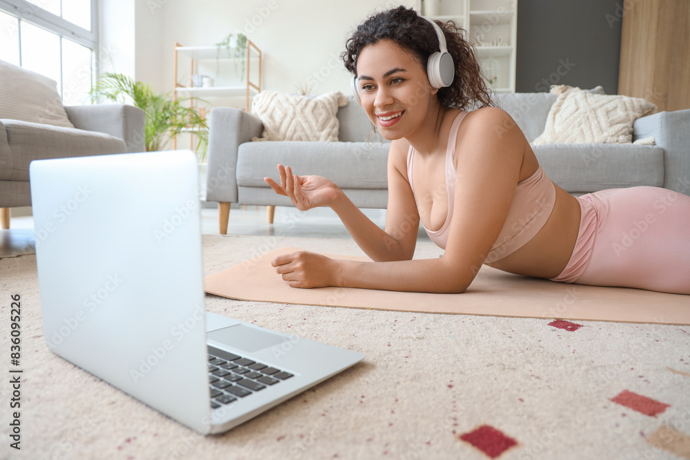 Sporty African-American woman video chatting with her online trainer on yoga mat at home Sporty African-American woman video chatting with her online trainer on yoga mat at home