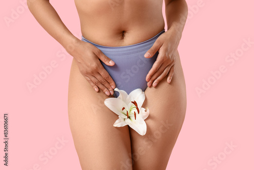 Beautiful young African-American woman in panties with white lily flower on pink background, closeup © Pixel-Shot