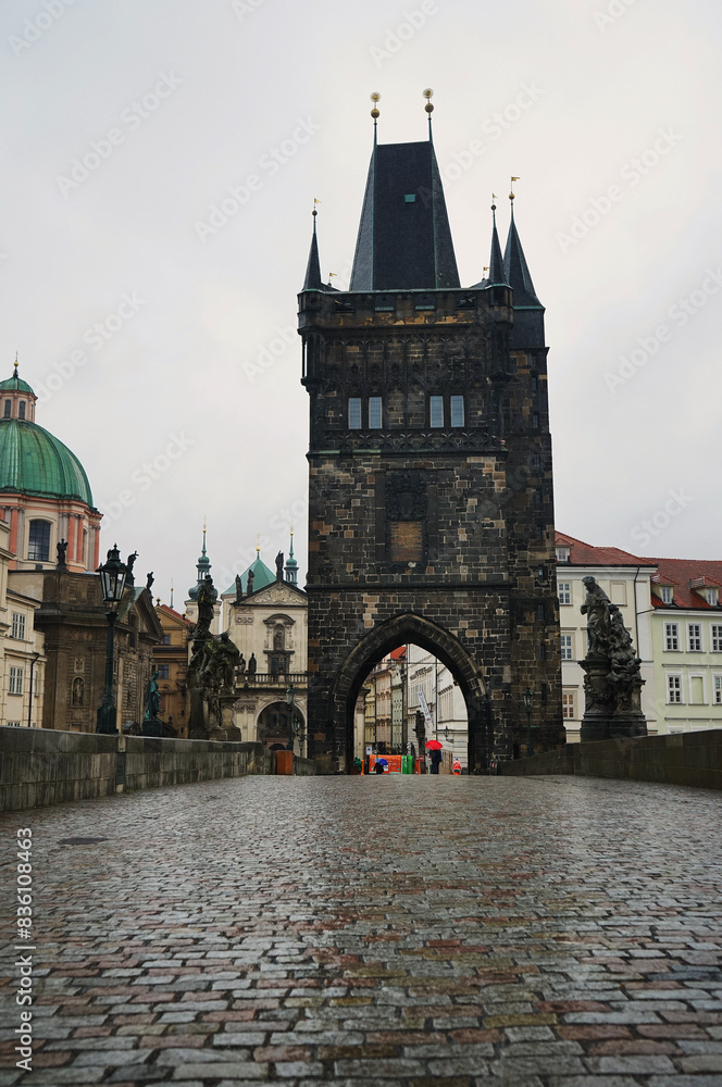 Charles Bridge with wet paving stones and historical buildings in rainy weather Charles Bridge with wet paving stones and historical buildings in rainy weather