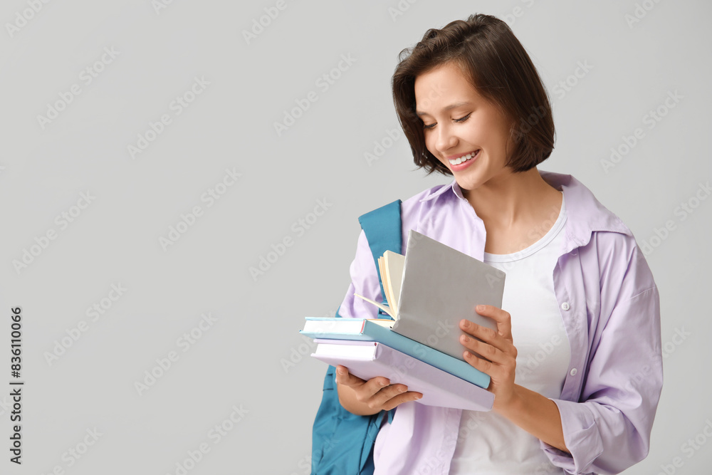 Beautiful female student with books and backpack on grey background Beautiful female student with books and backpack on grey background