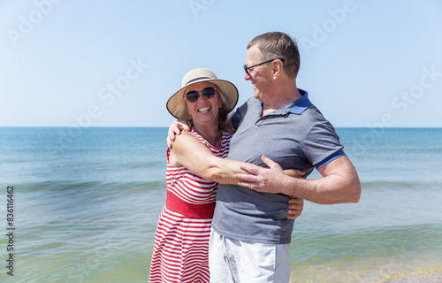 An elderly man and woman hugging on the seashore on a sunny day. Love and tenderness. A happy family.
