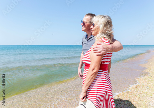 An elderly man and woman hugging on the seashore on a sunny day. Love and tenderness. A happy family.