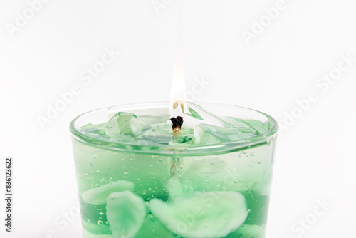 Trendy gel candle in the form of a mojito with ice on white background. Flame closeup
