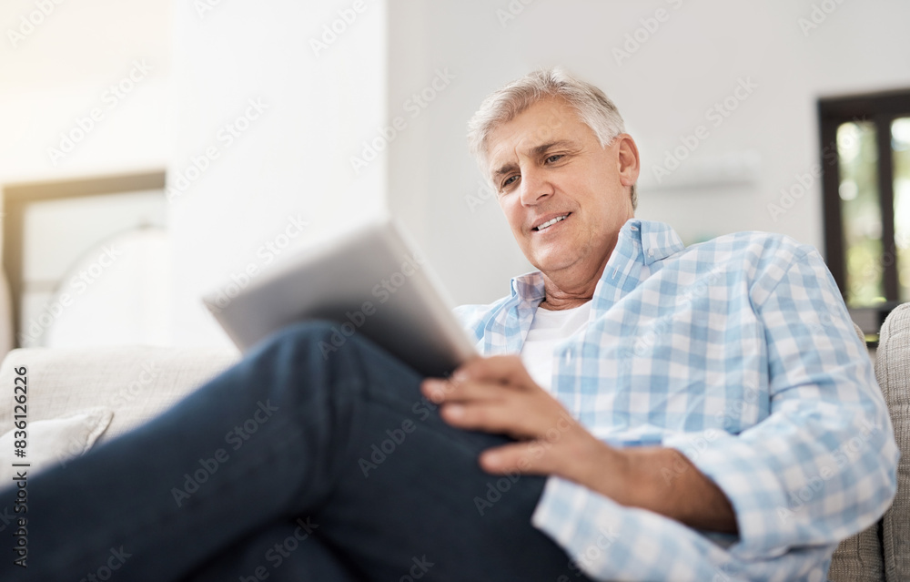 Smile, tablet and mature man on sofa for communication, networking or reading news article in living room. Online, technology and person for watching video, browsing internet or social media in home Smile, tablet and mature man on sofa for communication, networking or reading news article in living room. Online, technology and person for watching video, browsing internet or social media in home