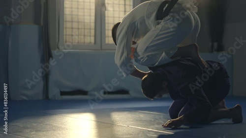 Jiu jitsu figter athlete training on sparring holding kimura lock submission on the opponents arm wearing kimono in slow-motion