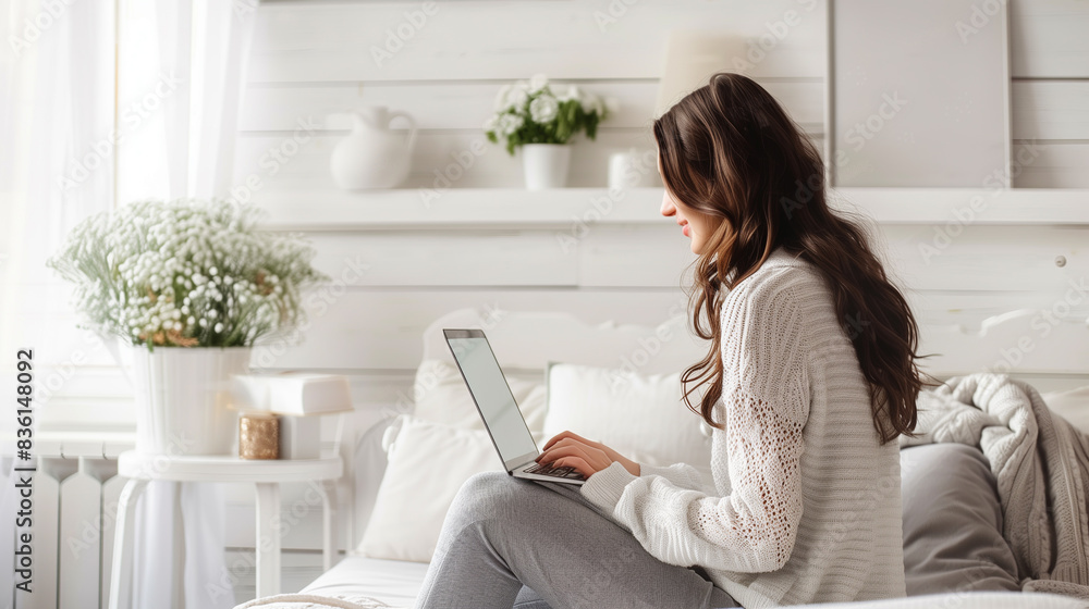 woman working on a laptop in white cozy room. woman working on a laptop in white cozy room.