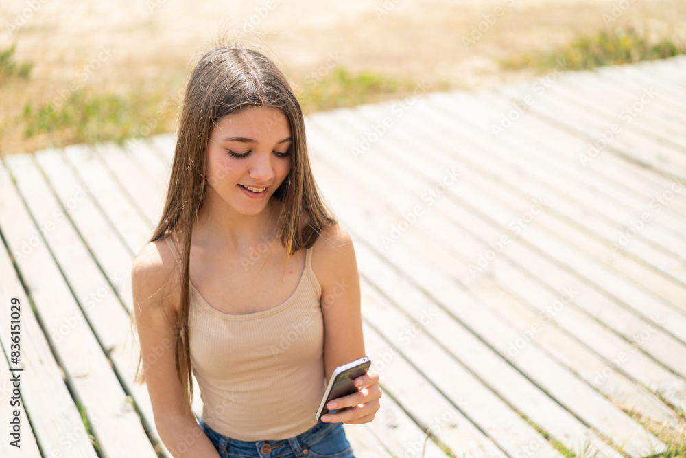 Teenager girl at outdoors sending a message or email with the mobile Teenager girl at outdoors sending a message or email with the mobile