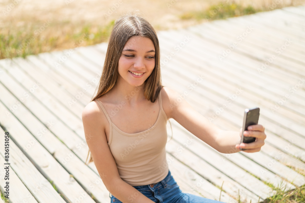 Teenager girl at outdoors making a selfie with mobile phone Teenager girl at outdoors making a selfie with mobile phone