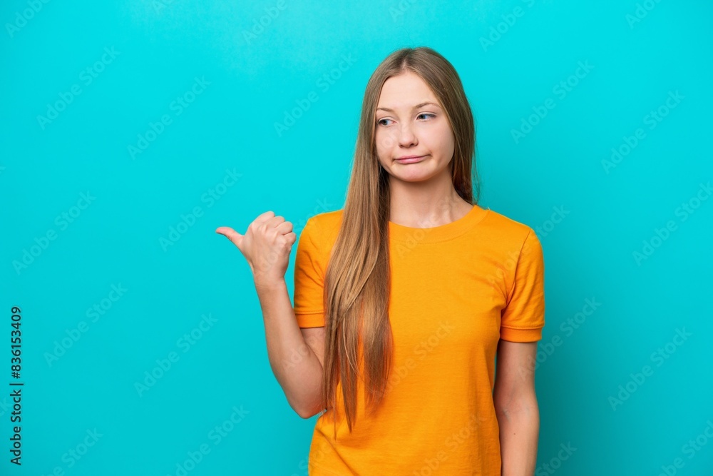 Young Russian woman isolated on blue background unhappy and pointing to the side Young Russian woman isolated on blue background unhappy and pointing to the side