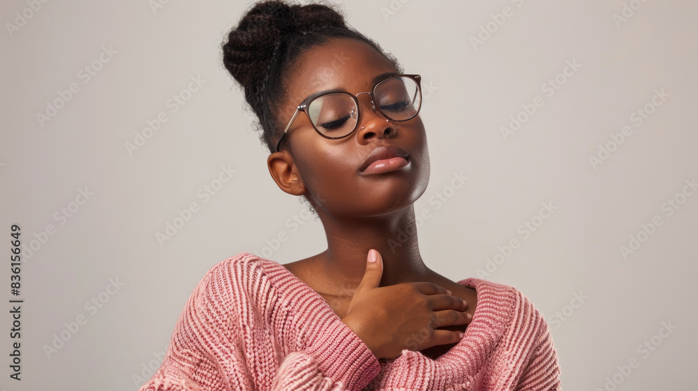 Naklejka premium A young woman wearing glasses and a pink sweater closes her eyes and takes a deep breath, enjoying a moment of peace and tranquility.