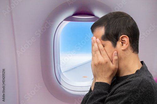 Close-up view of a man covering his face and crying.Headache in the airplane, man passenger afraid and feeling bad during the flight in plane © cunaplus