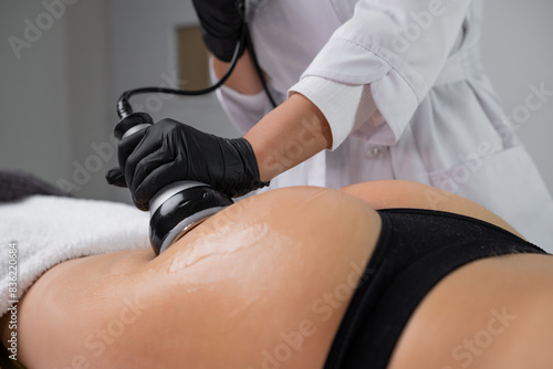 Young woman is in the process of body contouring using ultrasound cavitation at a beauty salon. 