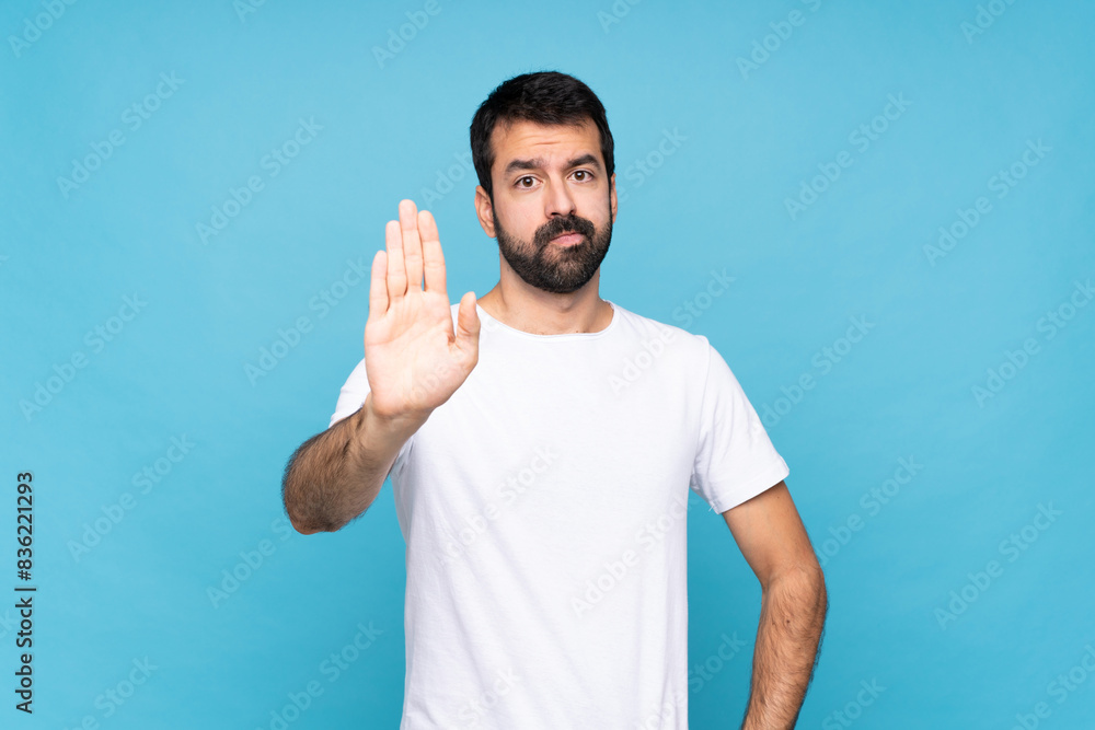 Young man with beard over isolated blue background making stop gesture Young man with beard over isolated blue background making stop gesture