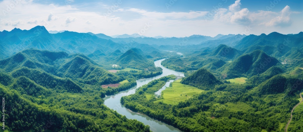 Naklejka premium Aerial drone shot of a picturesque river in the lush green tropical forest of Southeast Asia with mountains in the backdrop, perfect for copy space image.