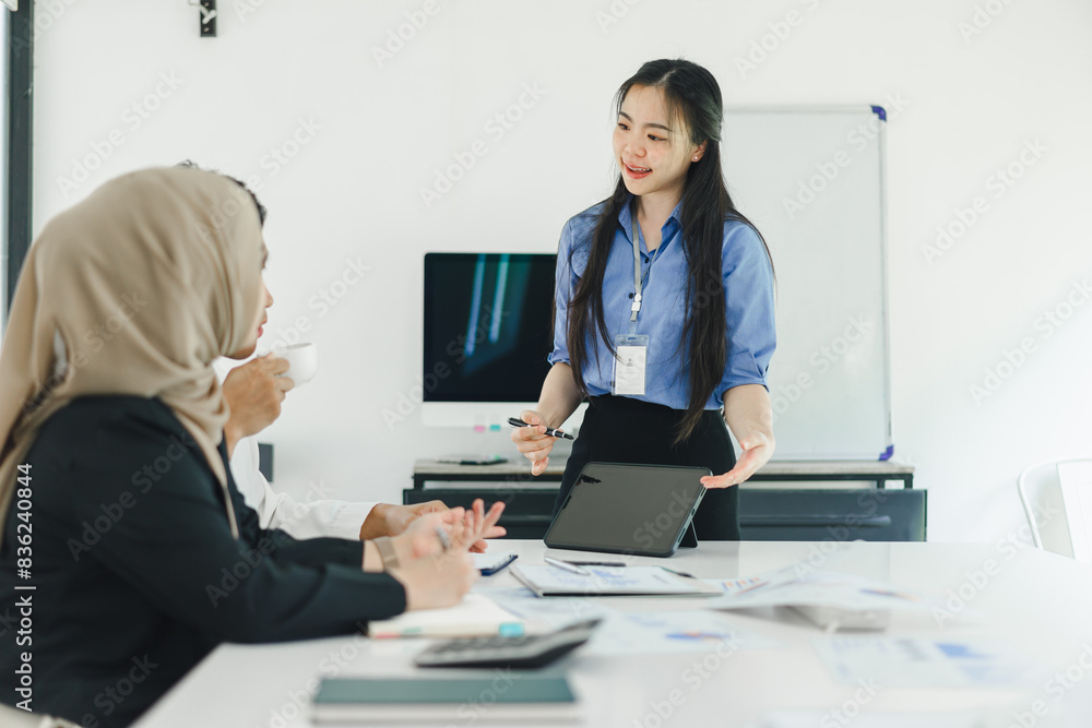 Diverse team working together on tablet in modern office. Diverse team working together on tablet in modern office.