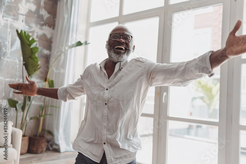 Positive elderly black man dancing in his house. Symbolizing joy and happiness, a wellbeing concept photo