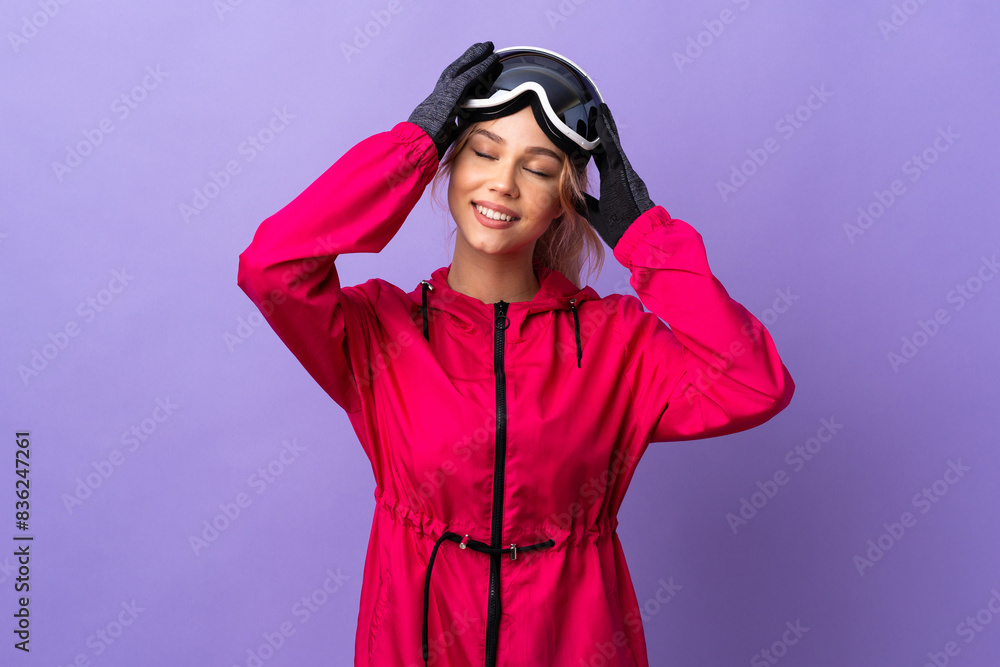 Skier teenager girl with snowboarding glasses over isolated purple background laughing Skier teenager girl with snowboarding glasses over isolated purple background laughing