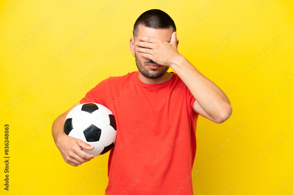 Young caucasian man playing soccer isolated on yellow background covering eyes by hands. Do not want to see something Young caucasian man playing soccer isolated on yellow background covering eyes by hands. Do not want to see something