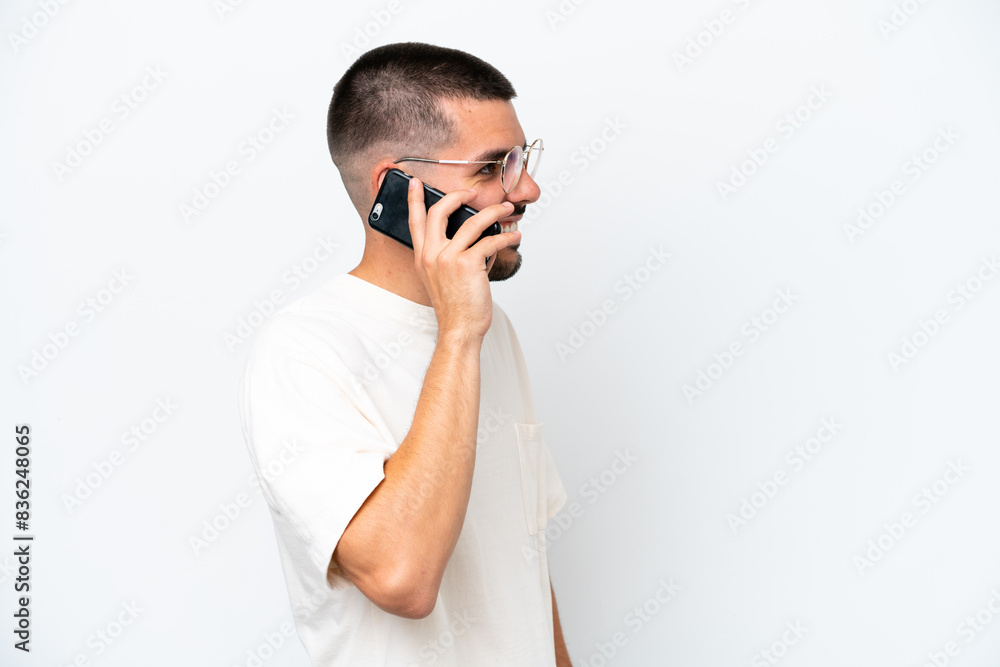 Young caucasian man isolated on white background keeping a conversation with the mobile phone with someone Young caucasian man isolated on white background keeping a conversation with the mobile phone with someone
